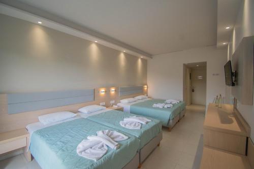 two beds in a hotel room with towels on them at Dennys Inn Hotel in Kalamaki