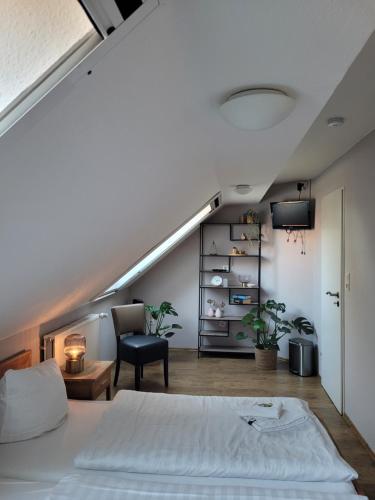 an attic bedroom with a bed and a chair at Hotel Garni Kastanjehoff in Timmel