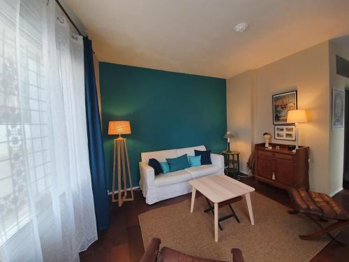 - un salon avec un canapé et un mur vert dans l'établissement L'Heure Bleue by Tranquil at Home, à Pornichet