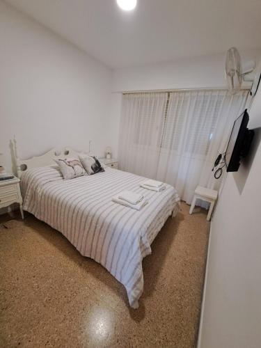 ein weißes Schlafzimmer mit einem großen Bett und einem Fenster in der Unterkunft Departamento frente al mar entre Guemes y Olavarria in Mar del Plata