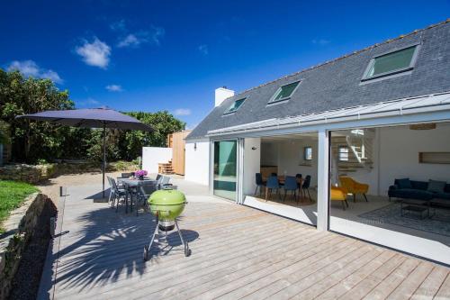 une terrasse en bois avec une table et un parasol dans l'établissement Tipoz'Immo-Ti Marin beach access - restaurants on foot - bed linen included, à Plovan