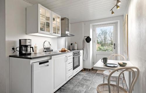 a kitchen with white cabinets and a table and a window at 2 Bedroom Nice Apartment In Aakirkeby in Åkirkeby
