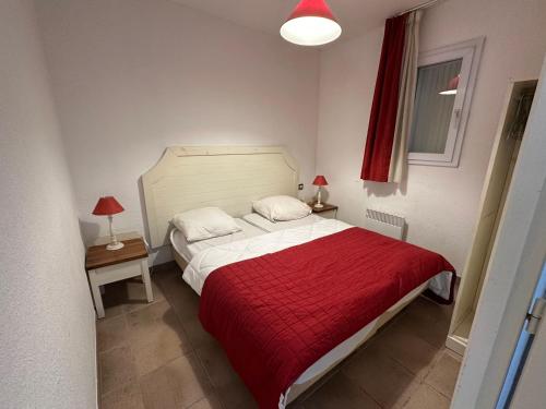 une chambre avec un lit avec une couverture rouge dans l'établissement Appartement - place de parking - terrasse vue mer, à Saintes-Maries-de-la-Mer