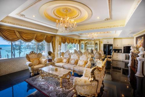 una sala de estar con muebles de oro y una lámpara de araña. en The Penthouse Seaview Rawai Beach Phuket by Benya Group - Free Airport Pick Up, en Phuket