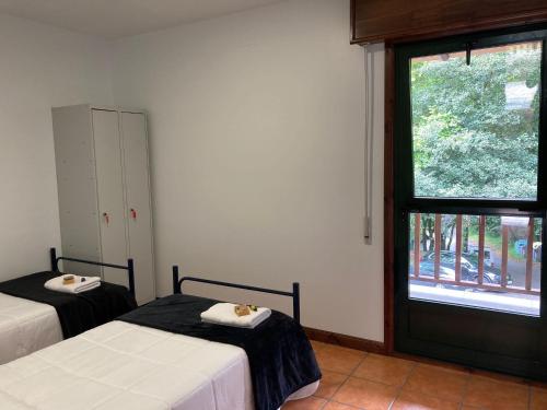 a bedroom with two beds and a large window at Albergue O Beque in Moaña