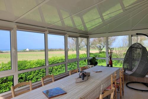 une salle à manger avec une table et une vue sur un champ dans l'établissement Tipoz'Immo Avel Moor sea view beach on foot ideal for groups, à Tréogat