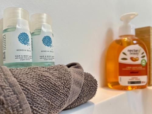 - une étagère avec 2 bouteilles de savon et une serviette dans l'établissement Au rythme des saisons - 364, à Rouen