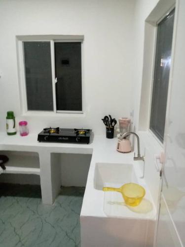 a white kitchen with a sink and a window at Uroa House in Uroa