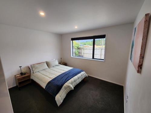 a bedroom with a bed and a window at Kaniere Hideaway in Hokitika