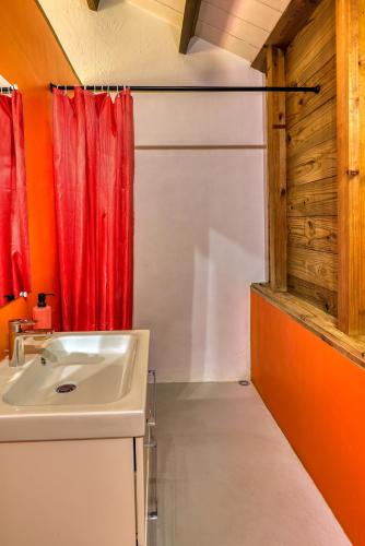 a bathroom with a sink and a red curtain at LES PECHEURS DU LAGON in Saint-Leu