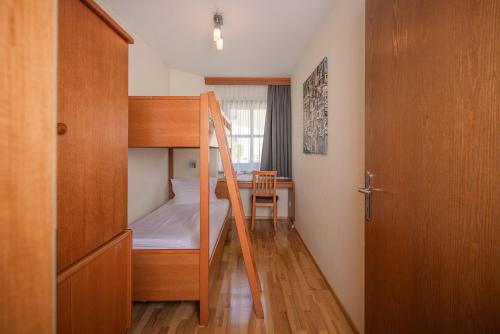 a small room with a bunk bed and a desk at Alpine Spa Residence in Bad Kleinkirchheim