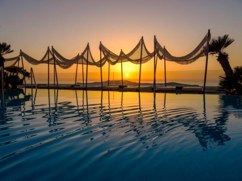 a swimming pool with a sunset in the background at Andromeda Villas & Spa Resort in Imerovigli