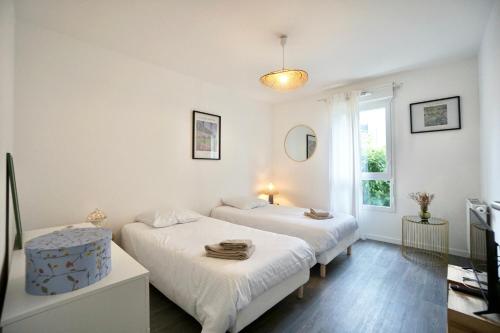 deux lits dans une chambre blanche avec une fenêtre dans l'établissement L'horizon -parking, à Concarneau