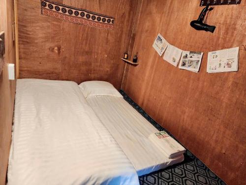 a small bed in a room with a wooden wall at TiTi House in Dồng Văn