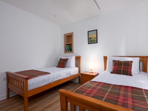 a bedroom with two beds and a table with a lamp at Golfers Haven Links Cottage Crail - Pass the Keys in Crail
