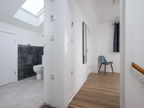 a white bathroom with a toilet and a chair at Golfers Haven Links Cottage Crail - Pass the Keys in Crail