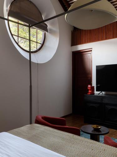 a bedroom with a bed and a tv and a window at The Bungalow Galle Fort - Hotel - Restaurant - Cocktail bar in Galle