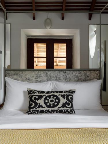 a bed with a black and white pillow on it at The Bungalow Galle Fort - Hotel - Restaurant - Cocktail bar in Galle