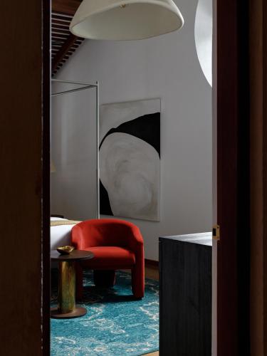 a living room with a red chair and a table at The Bungalow Galle Fort - Hotel - Restaurant - Cocktail bar in Galle