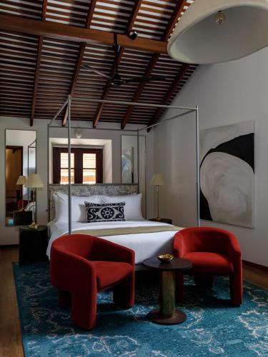 a bedroom with a bed and two red chairs at The Bungalow Galle Fort - Hotel - Restaurant - Cocktail bar in Galle