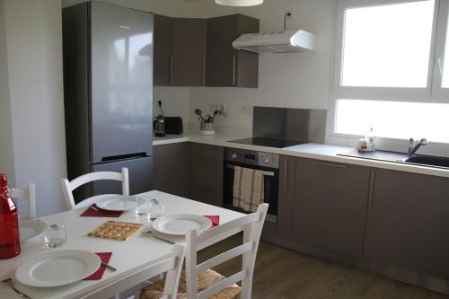 - une cuisine avec une table et une table et des chaises blanches dans l'établissement Fromentin - Parking - calme - proche port, à Vannes