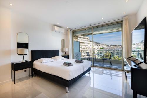 une chambre avec un lit et une grande fenêtre dans l'établissement Agence des Résidences - Appartements privés du 45 CROISETTE- Prestige, à Cannes