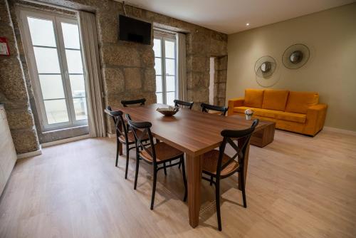 a dining room with a table and chairs and a couch at HAGAH Alojamentos in Guimarães
