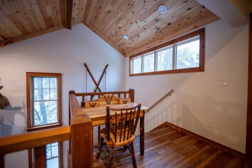 a dining room with a wooden table and two windows at Luxury House in Pocono Mountains in Tannersville