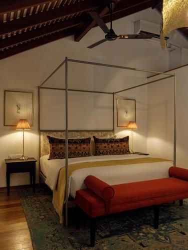 a bedroom with a canopy bed and a red bench at The Bungalow Galle Fort - Hotel - Restaurant - Cocktail bar in Galle