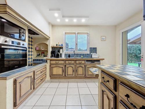 une grande cuisine avec des placards en bois et une grande fenêtre dans l'établissement La Flemme en Rose- Villa avec piscine-Pet Friendly, à Peyriac-de-Mer