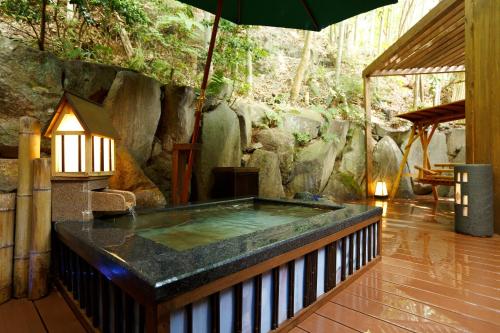 a hot tub in a room with an umbrella at Hakone Kamon in Hakone