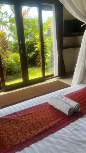 a bed with two towels on it in front of a window at Heaven Villa Ubud in Ubud