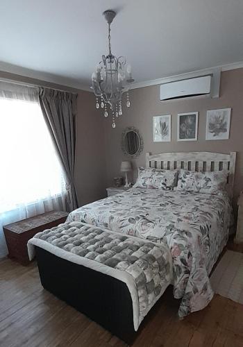 a bedroom with a large bed and a chandelier at De Kleine Herberg in Durbanville