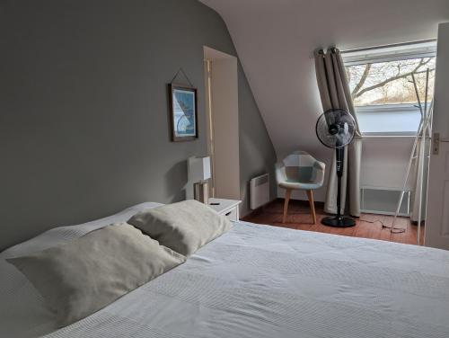 - une chambre avec un lit blanc et un ventilateur dans l'établissement Maison proche Mer, à Pénestin