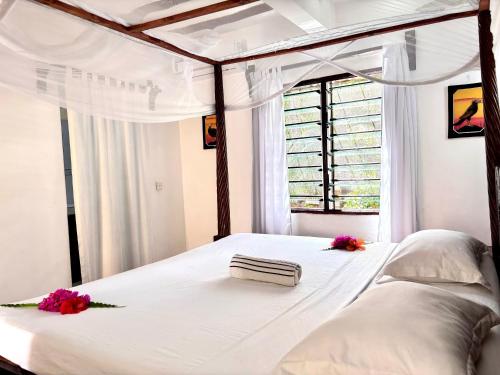 a bedroom with a white bed with flowers on it at Tembo village Watamu in Watamu