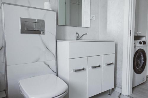 a white bathroom with a toilet and a sink at Lake View Apartment Iasi in Valea Lupului