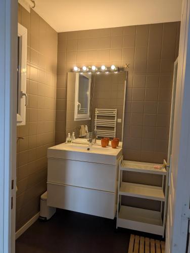 une salle de bain avec un lavabo et un miroir dans l'établissement Maison proche Mer, à Pénestin