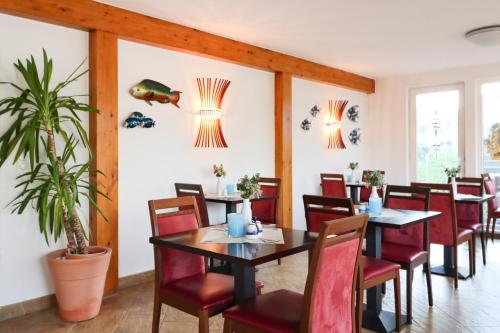 ein Esszimmer mit Tischen, Stühlen und einer Pflanze in der Unterkunft Aparthotel Leuchtfeuer Rügen in Glowe