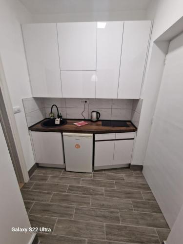 a small kitchen with white cabinets and a sink at Park Oaza in Čačak