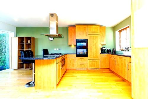 a kitchen with wooden cabinets and a black counter top at Spacious 4-Bed Bristol | WiFi | Parking | Workspace in Bristol