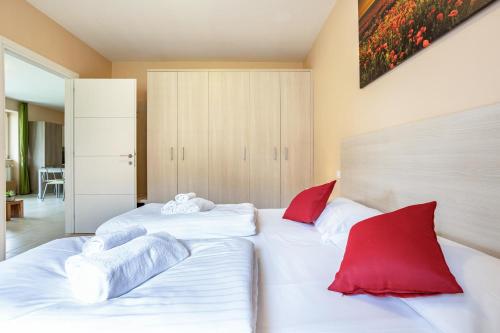 two beds in a bedroom with red and white pillows at Residence La Villa Principe in Tignale