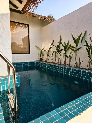 a swimming pool in a house with palm trees at SinQ Anvaya in Maem