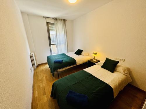 une chambre avec deux lits et une fenêtre dans l'établissement El mirador de César Augusto, à Saragosse