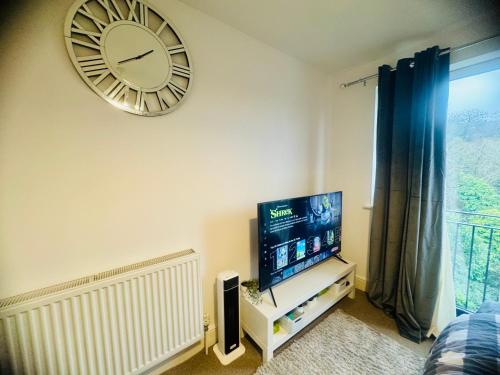 a clock on the wall above a television in a room at Apartment near Luton Airport, Train Station & Football Club in Luton