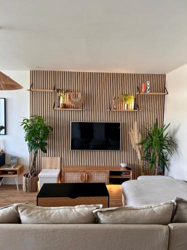 un salon avec un canapé et une télévision dans l'établissement Appartement T2 au bord du lac, à Bruges