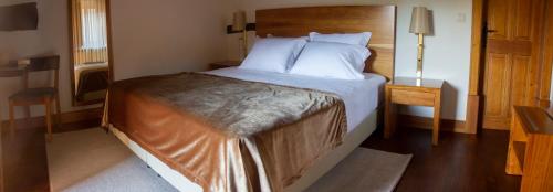 a bedroom with a large bed with a wooden headboard at Refúgios do Pinhal in Oleiros