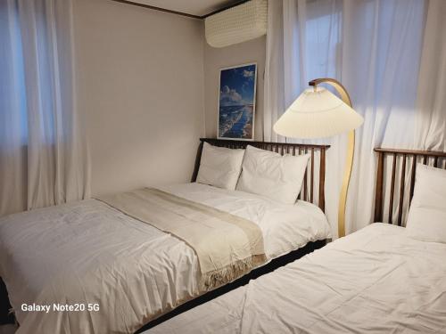 a bedroom with two beds and a lamp at Stay Yuyeon in Busan