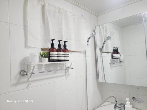 a bathroom with a sink and a shower with bottles on a shelf at Stay Yuyeon in Busan