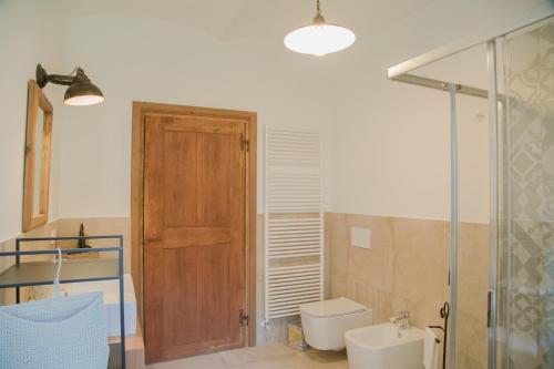 a bathroom with a toilet and a wooden door at Cascina Voglietti in Murisengo