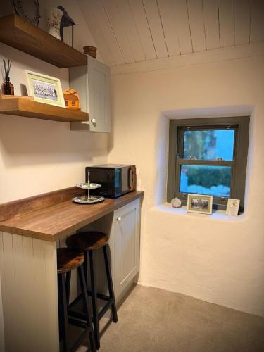 a kitchen with a counter with a microwave and a window at Murphys Thatched Cottage in Mitchelstown